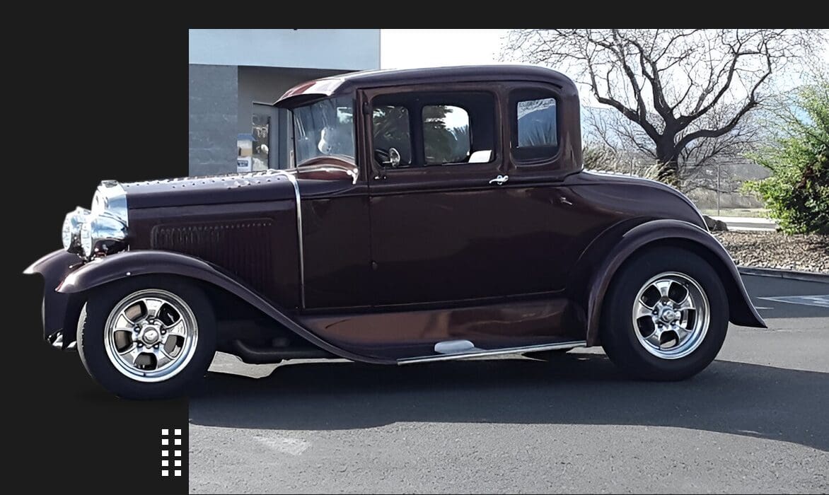 A vintage car parked on the side of a road.