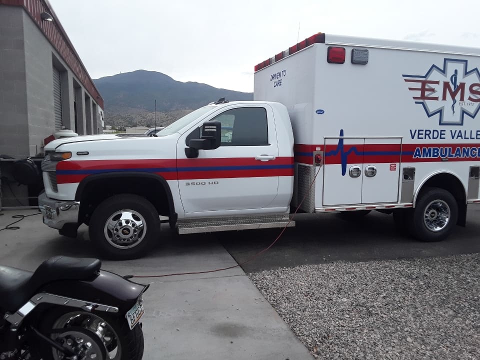 A white truck with red stripes parked in front of a building.