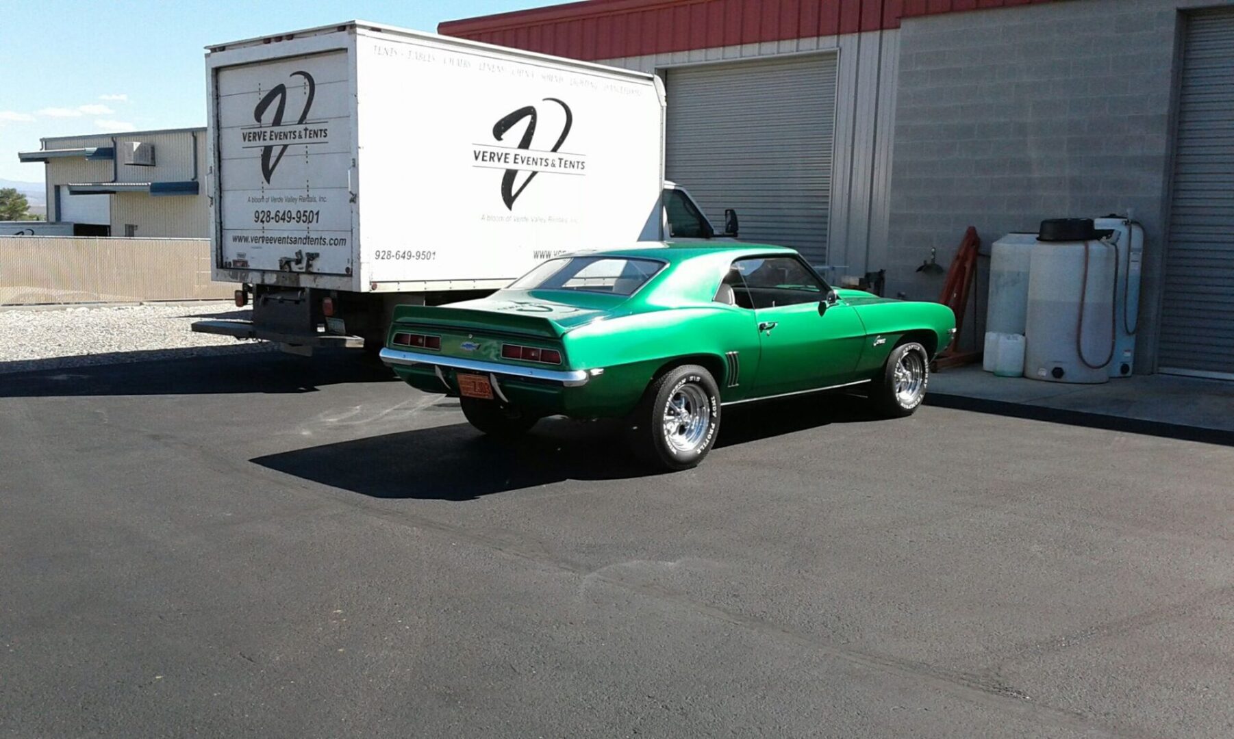 A green car parked in front of a white truck.